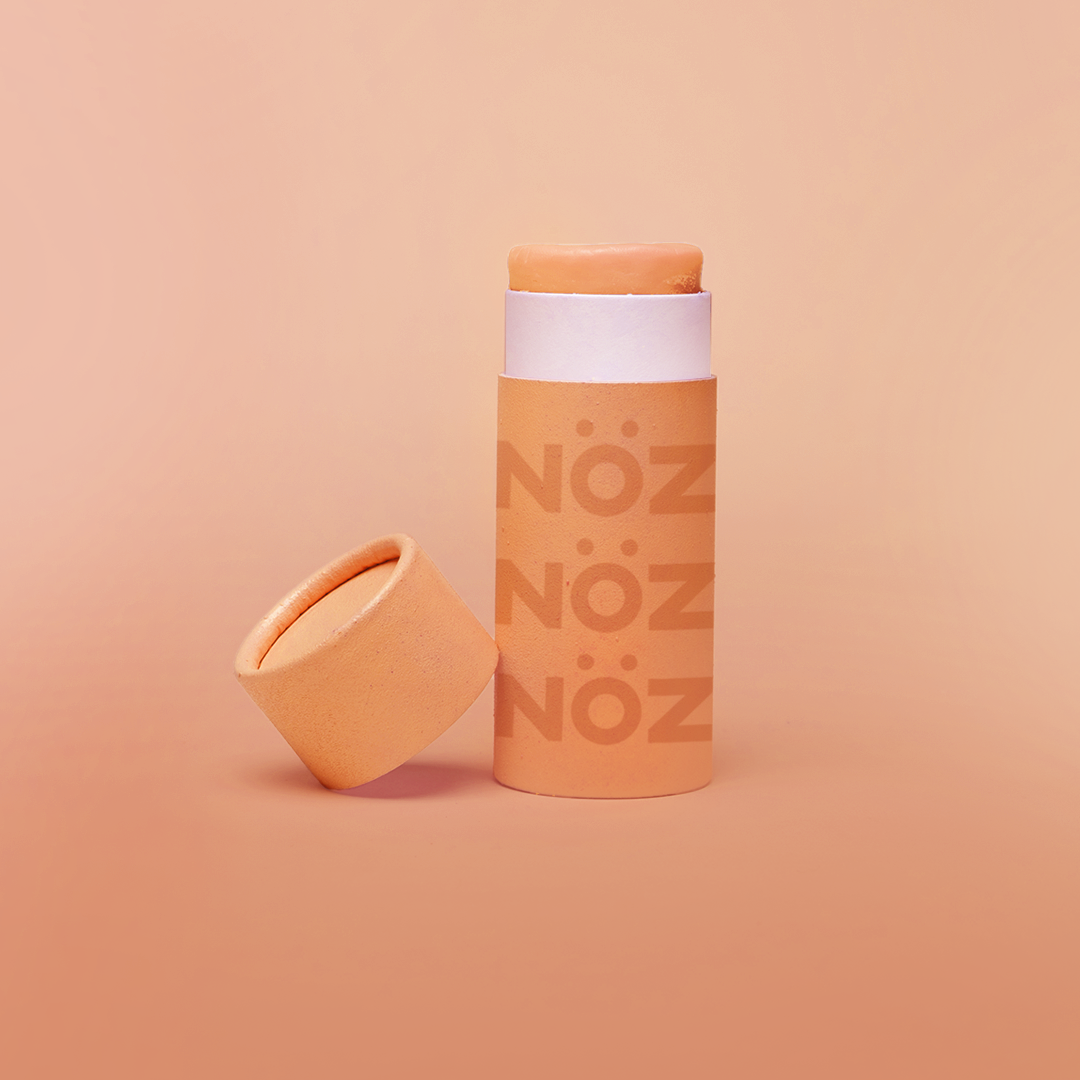 Orange  Nözscreen sunscreen stick with lid to the left against a orange background 