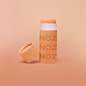 Orange  Nözscreen sunscreen stick with lid to the left against a orange background 